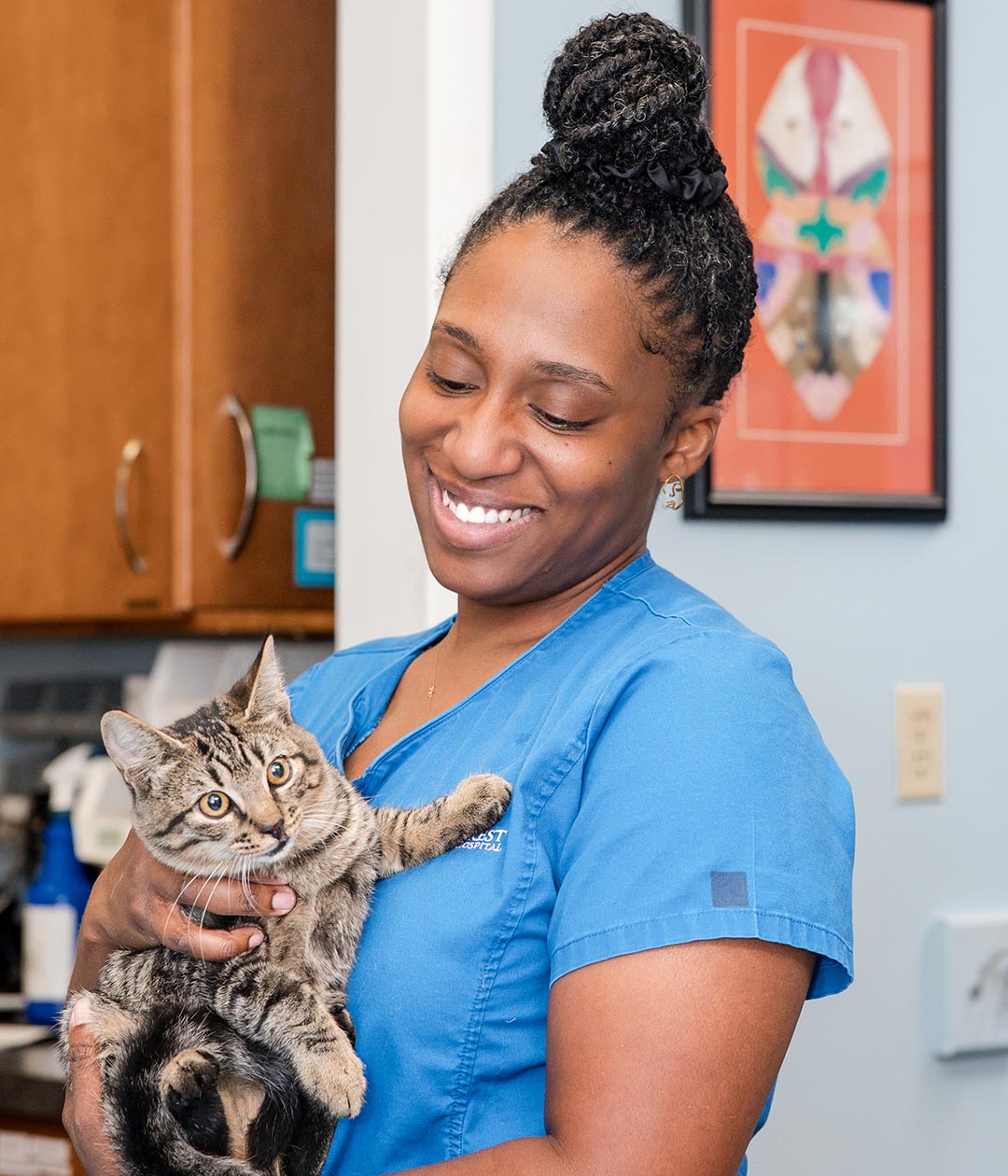 female staff member smiling while holding striped cat
