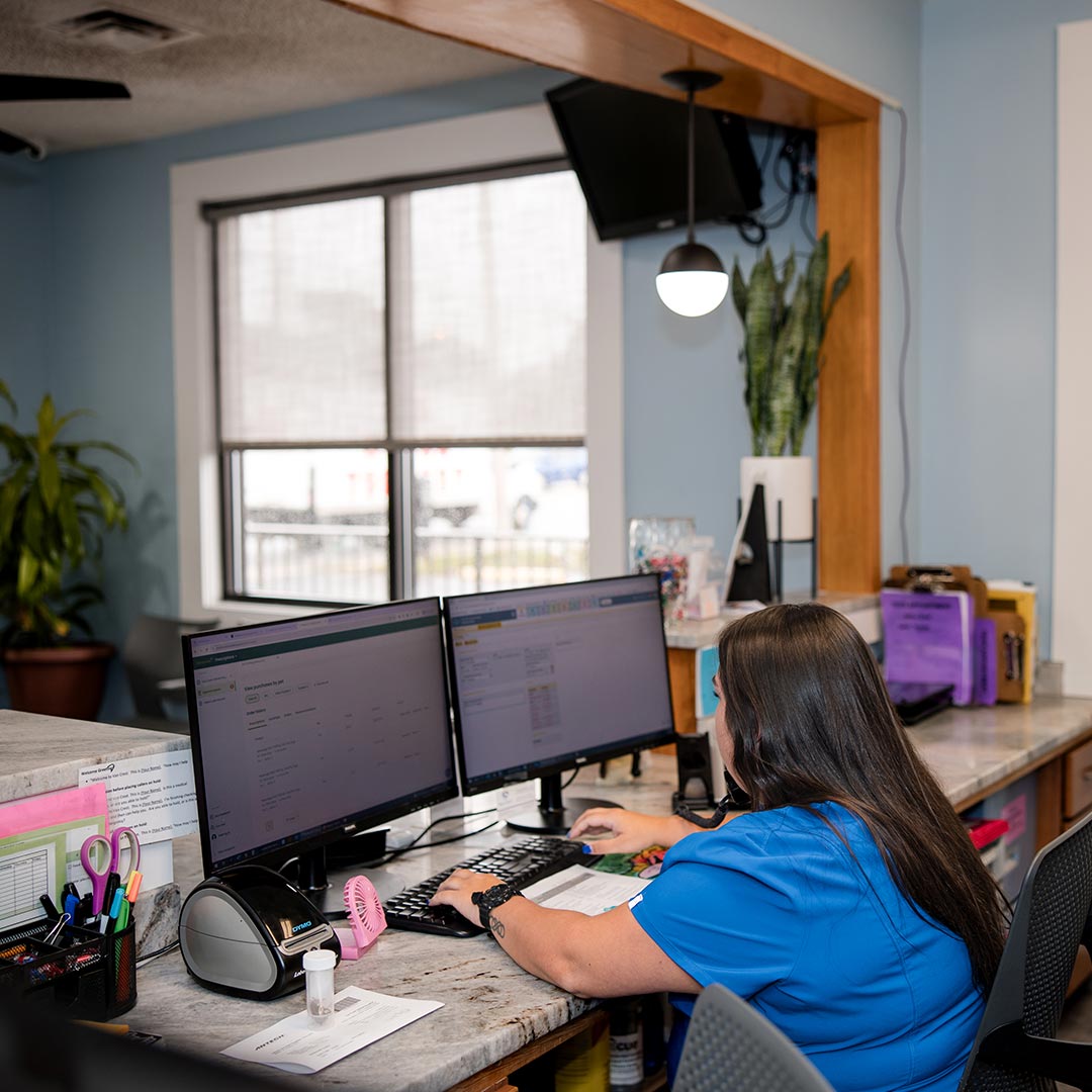 female receptionist using computer with dual monitors at front desk