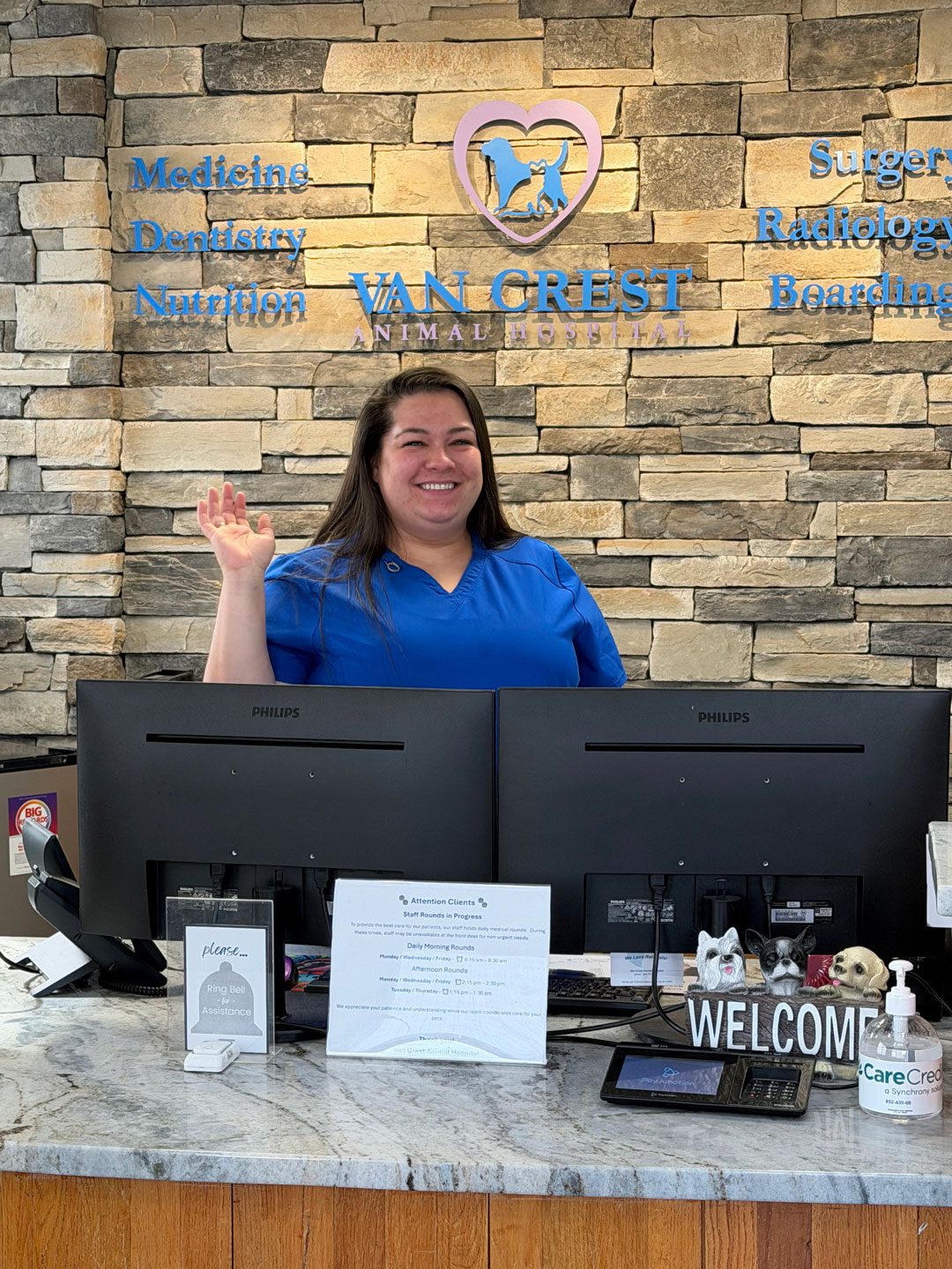 smiling receptionist standing behind front desk and waving